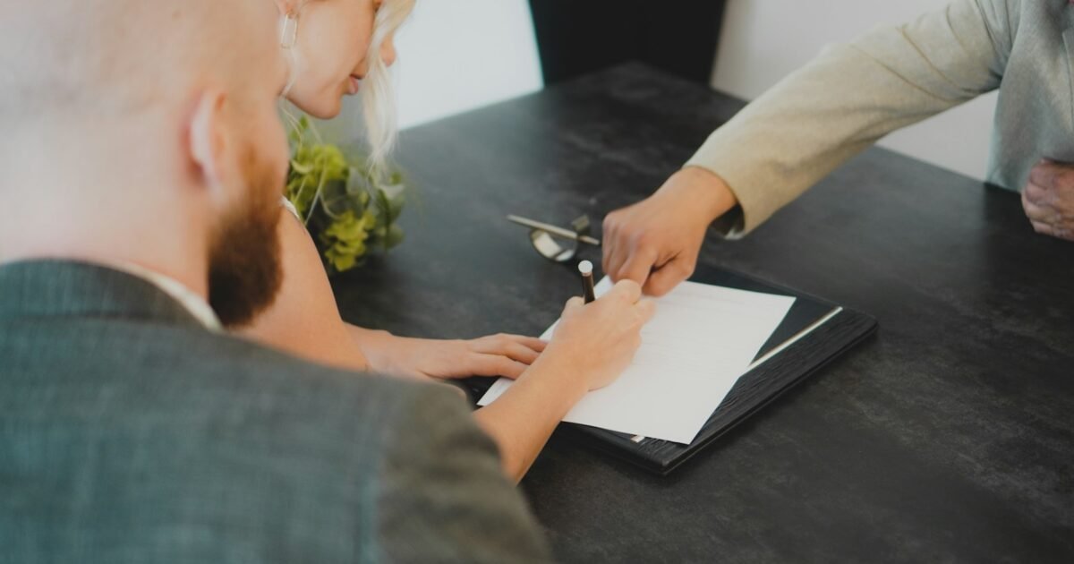 casal assinando documento sobre a mesa