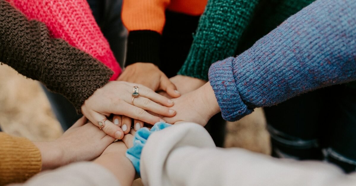 grupo de pessoas empilhando as mãos