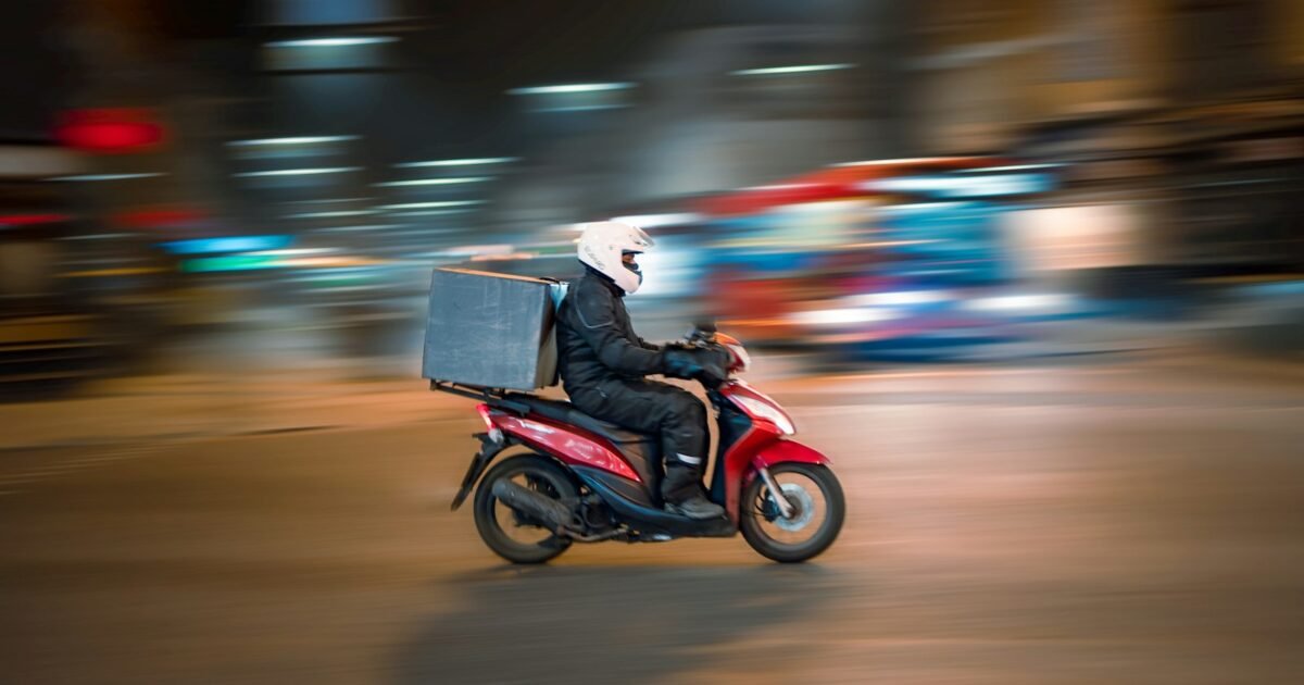 entregador de scooter vermelha circulando pela cidade